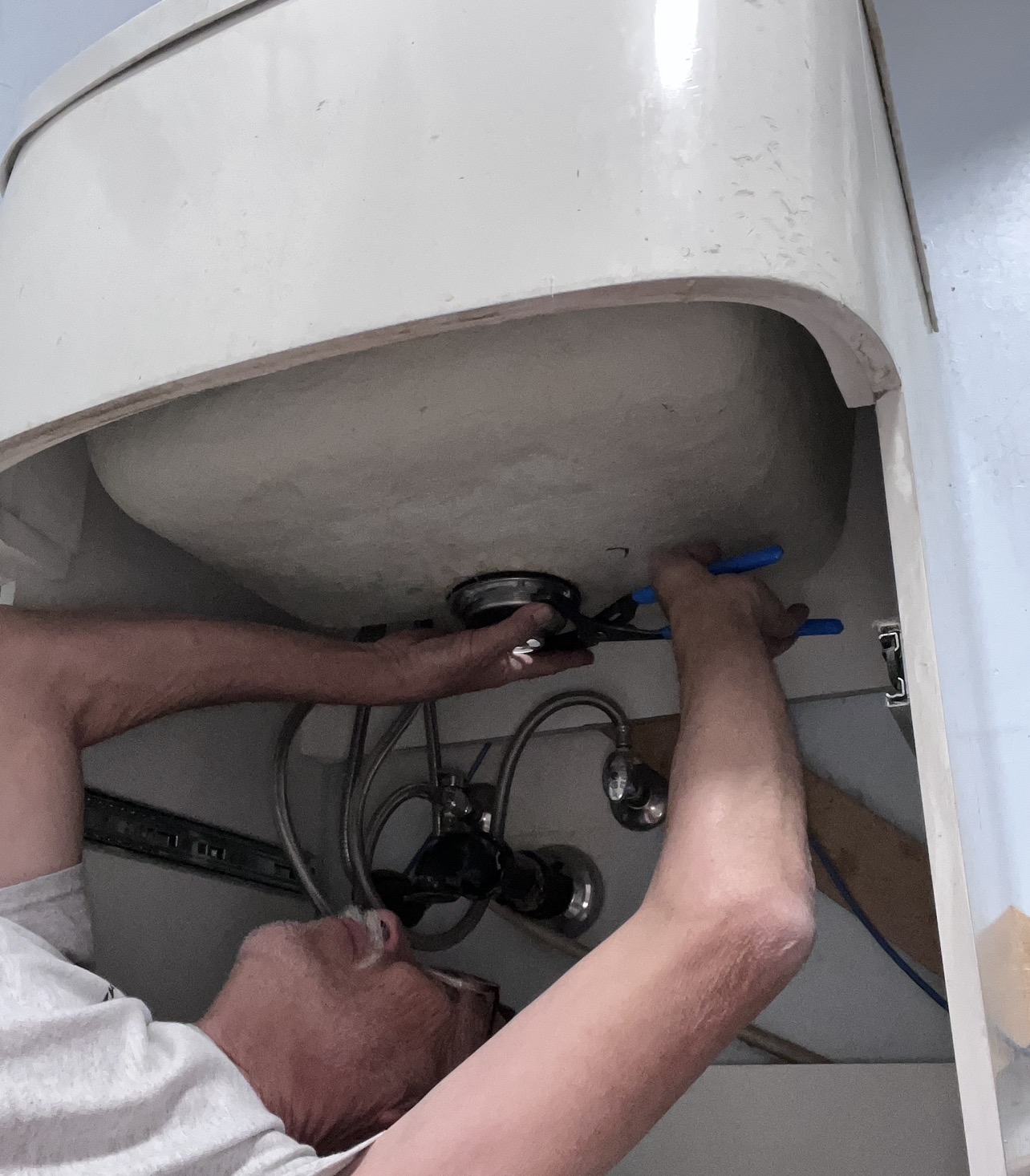 Plumber working on supply lines under a bathroom sink
